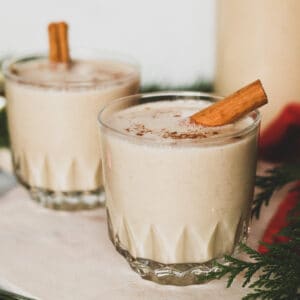 two gluten free dairy free eggnog drinks with cinnamon stick in each drink
