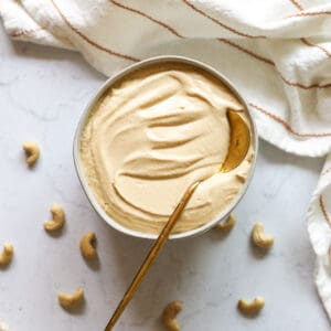 Cashew Cream Sauce Vegan in a white bowl with a gold spoon in the bowl