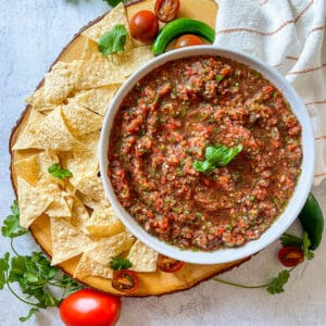 Homemade fresh salsa with chips served on a wood platter