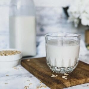 homemade oat milk in a glass on a cutting board