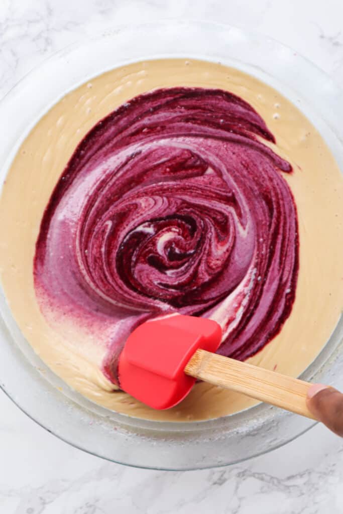 mixing blueberry sauce into cheesecake
