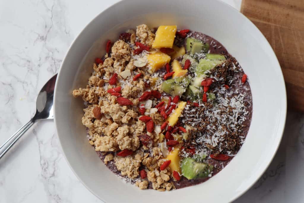 acai bowl made with protein powder acai and frozen fruit in a bowl with granola goji berries and sliced fruit