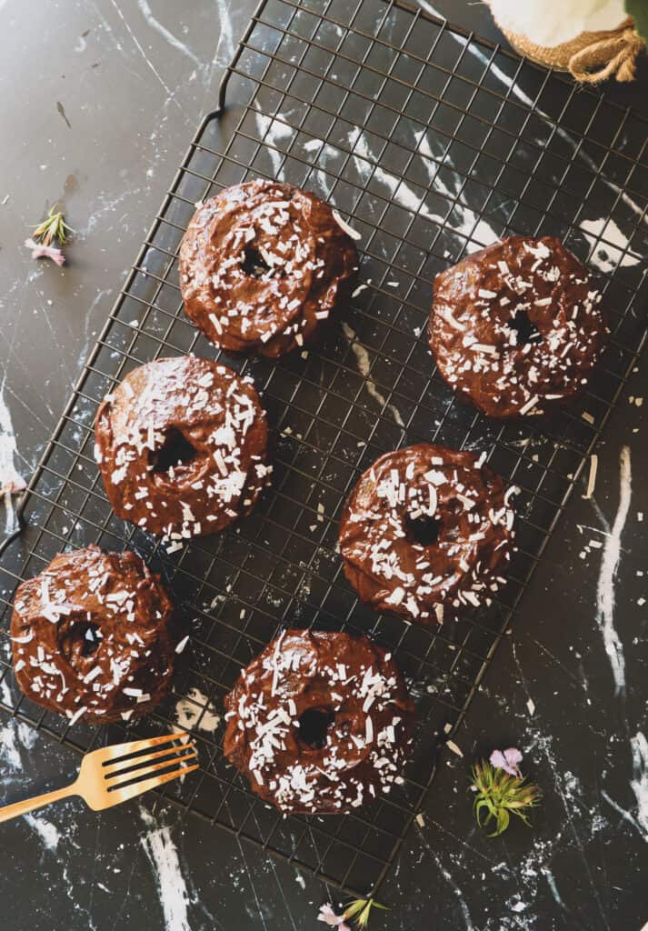 Overhead view of homemade chocolate baked donuts on a cooling rack,