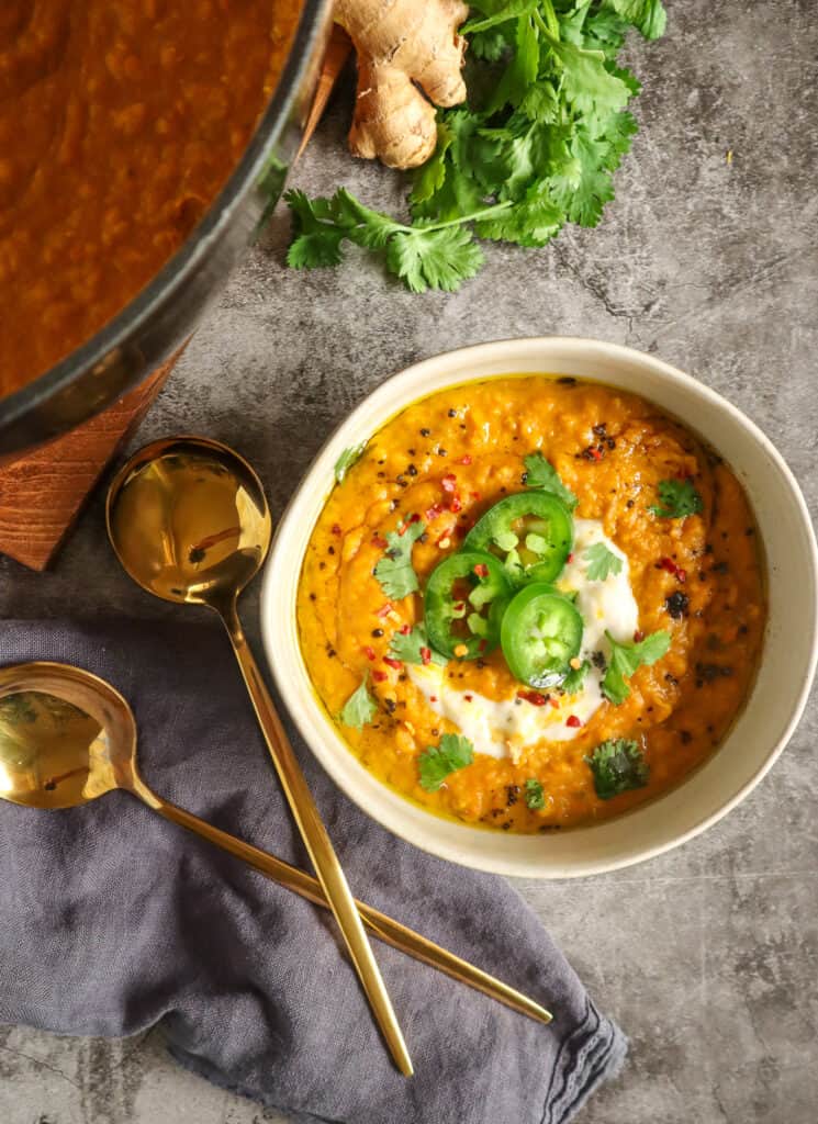 bowl of carrot lentil soup topped with jalapenos, dairy free yogurt, and cilantro