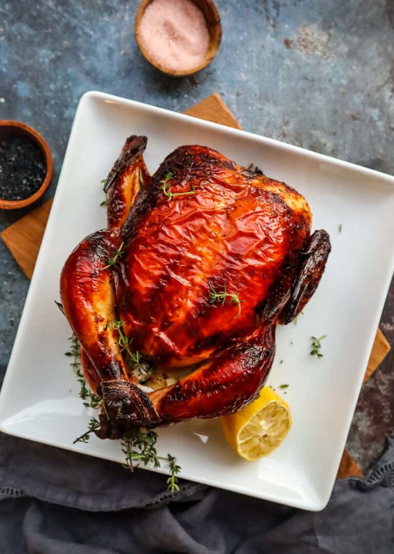 whole buttermilk roasted chicken on a plate with a wedge of lemon