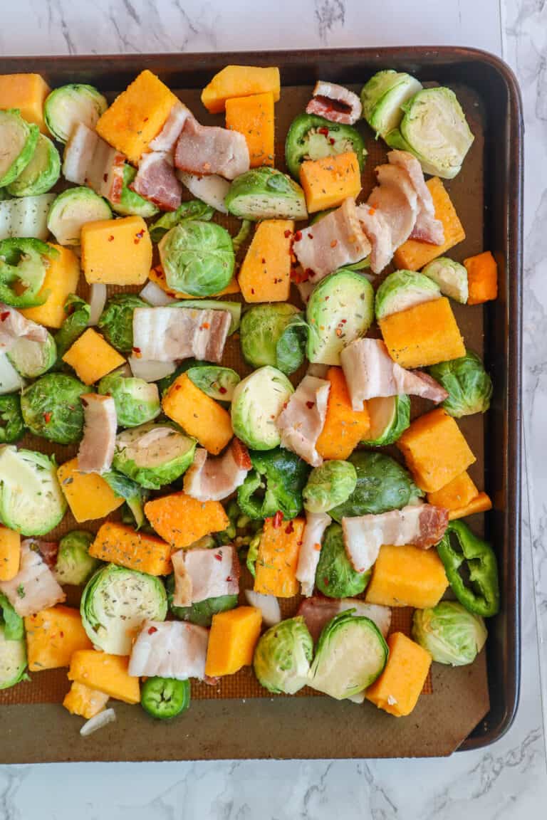 raw brussel sprouts, bacon, and butternut squash on a sheet pan for the oven
