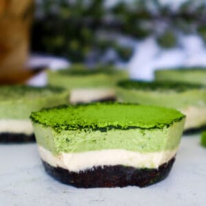 Close up of vegan matcha cheesecake to show layers of matcha cheesecake, vanilla cheescake, and oreo crust