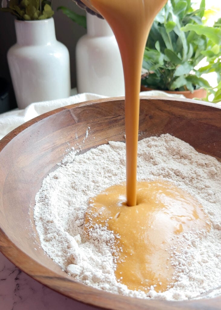 pouring sweet potato mixture in a bowl of flour