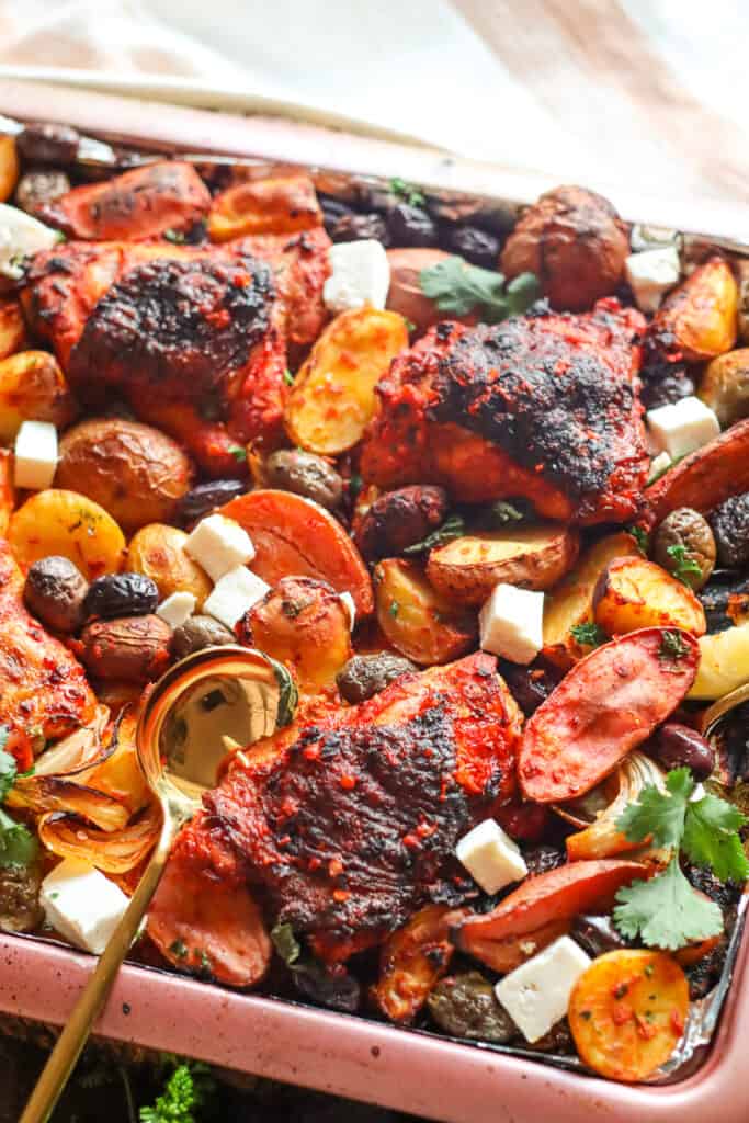 Roasted Harissa Chicken Thigs with Potatoes, feta, olives, and herbs on a sheet pan