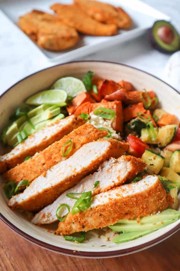 gluten free crispy air fryer chicken, sliced and added to a bowl with lentils, zucchini, sweet potato, avocado, and lime