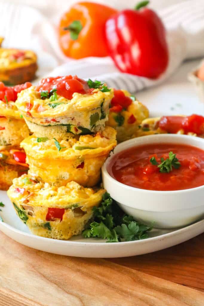 close up of stacked egg muffins to show texture, with a small ramekin of salsa on the side