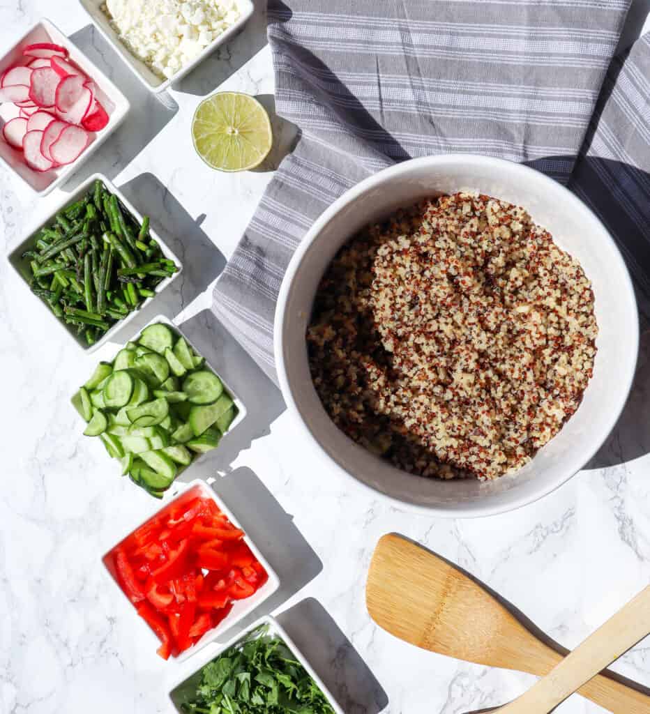 Ingredients to make Quinoa Vegetable Salad: cucumbers, peppers, radish, feta cheese, cooked quinoa, lime