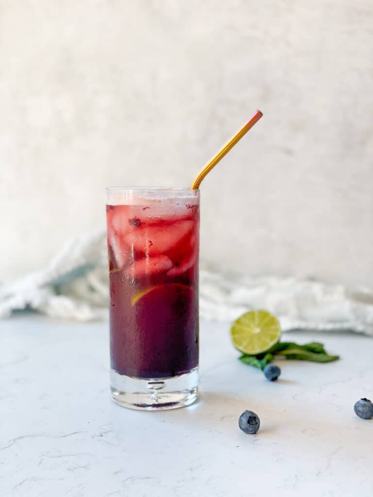 blueberry espresso tonic in a glass with a straw