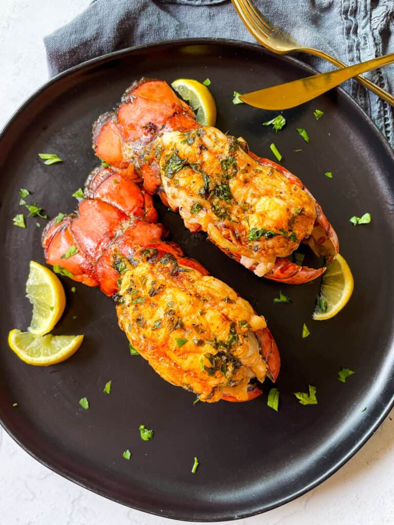 Juicy Garlic Butter Lobster Tails with lemon wedges. 