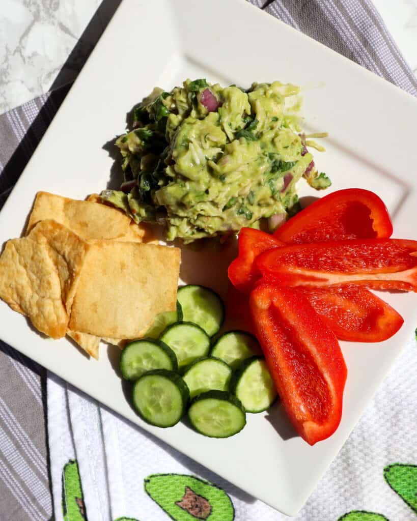 healthy avocado chicken salad served with peppers, cucumbers, and pita chips