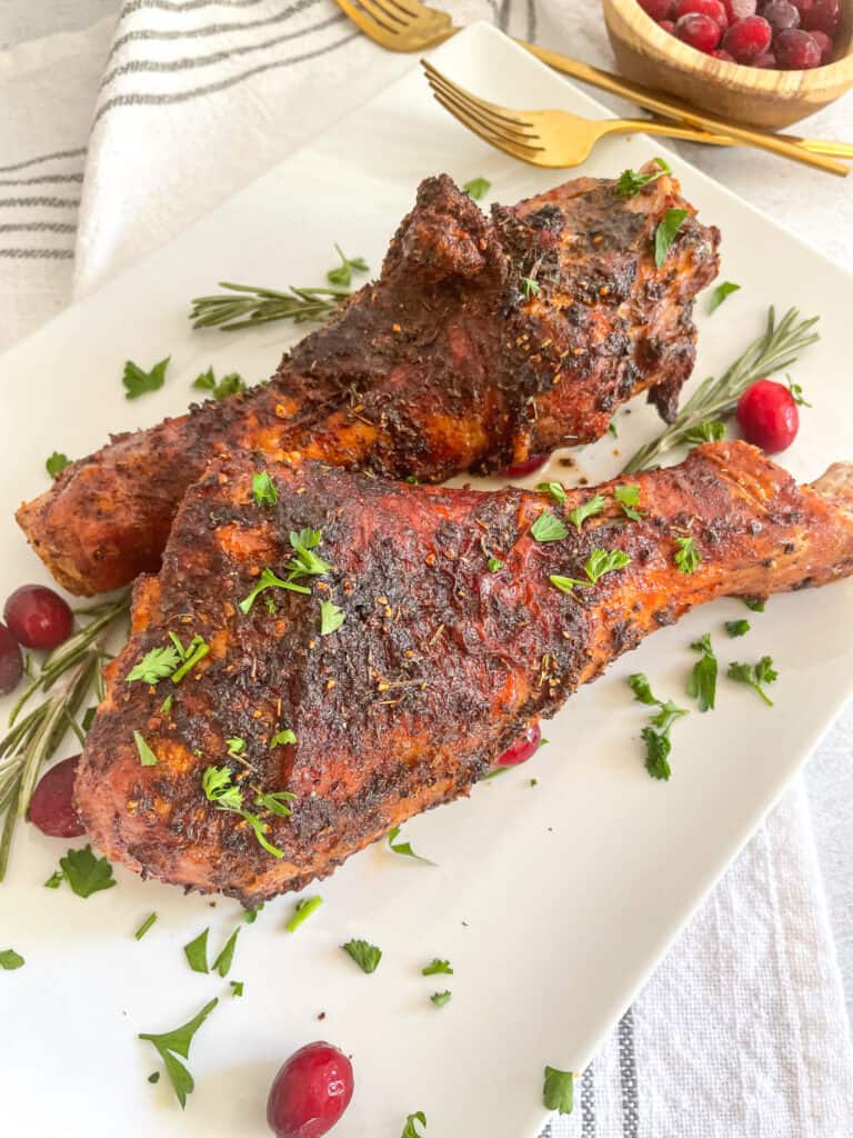 Air Fryer Turkey Legs garnished with rosemary, cranberries, and parsley