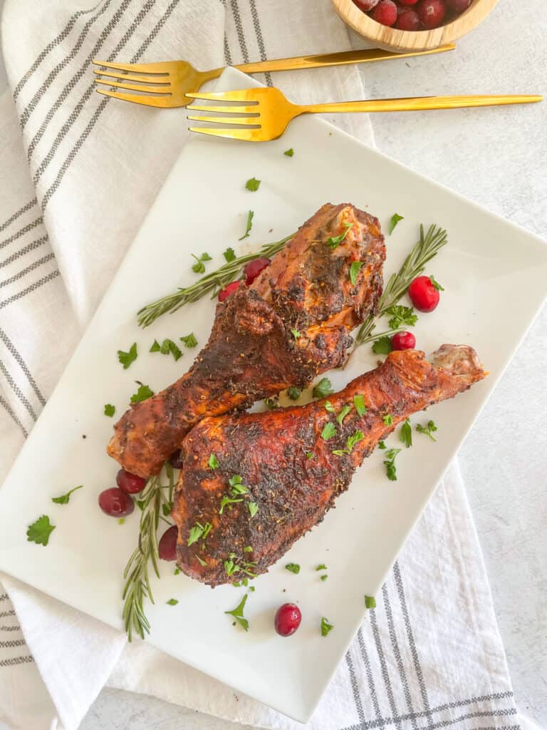 Air Fryer Turkey Legs garnished with rosemary, cranberries, and parsley