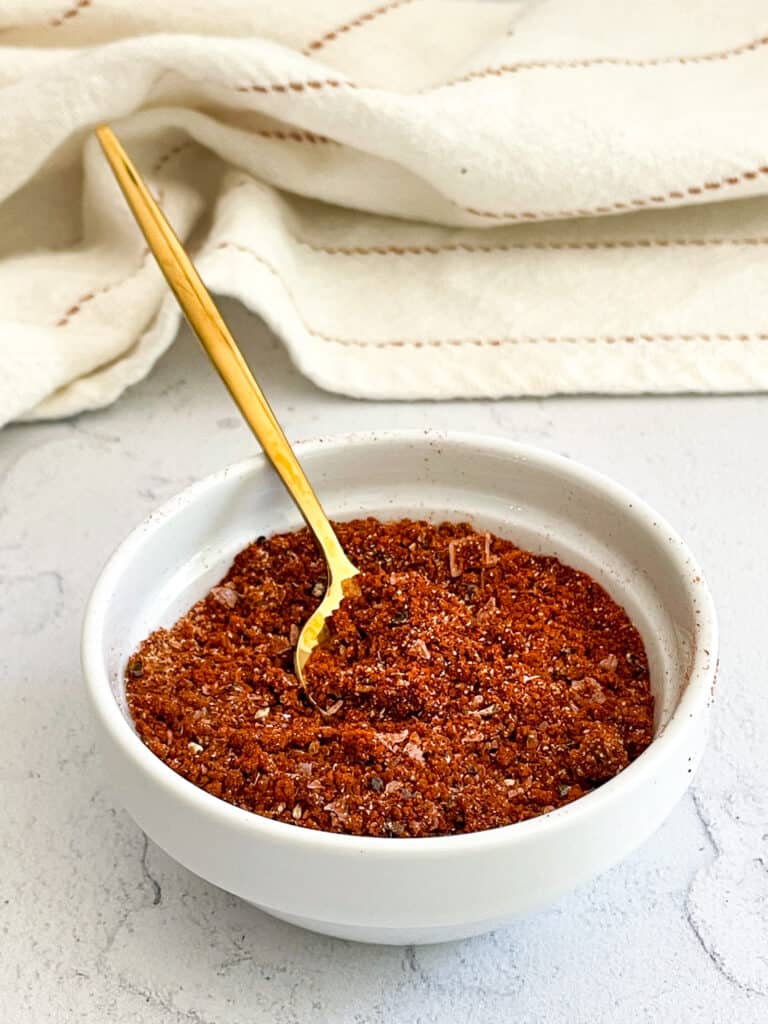 A white bowl full of dry rub for Instant Pot Ribs with a gold spoon inserted into the mix.