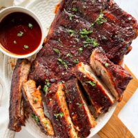 Instant Pot Barbecue Ribs on a white plate with a small bowl of homemade barbecue sauce on the side.