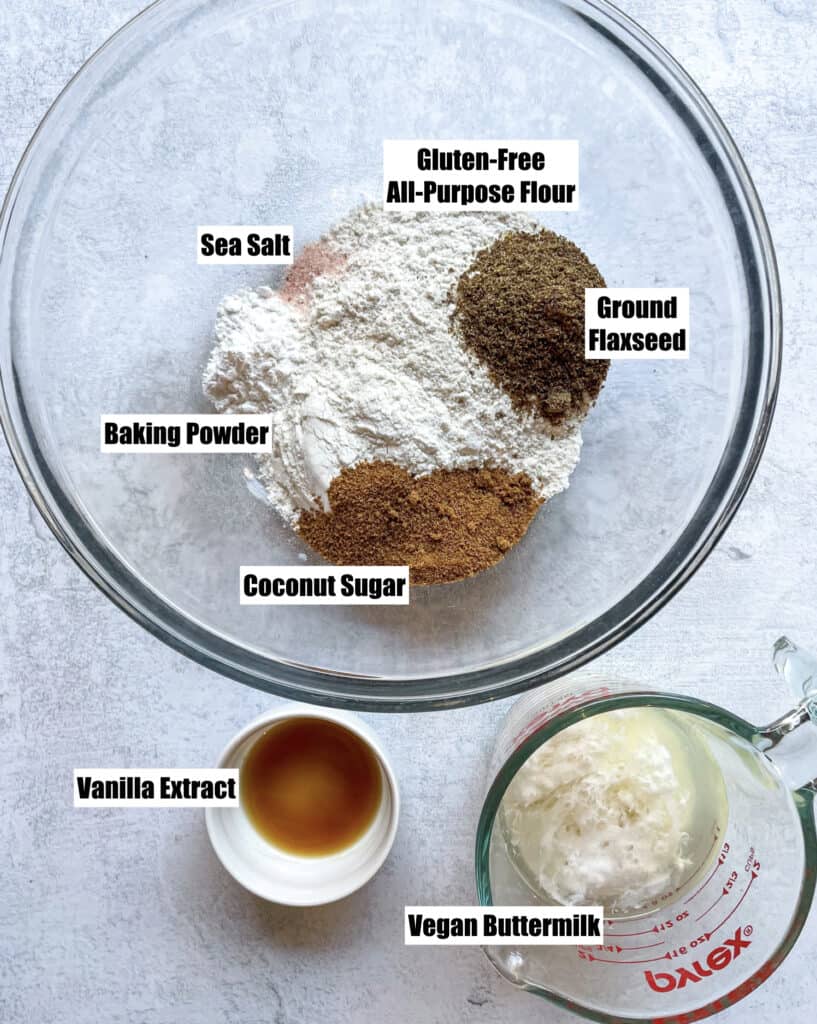 ingredients needed to make vegan gluten free pancakes shown are gluten free flour, sea salt, coconut sugar, baking powder, vanilla extract, vegan buttermilk