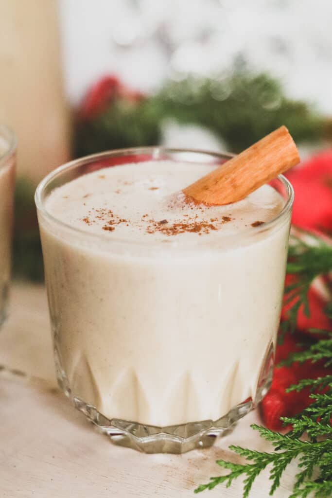 close up of dairy-free eggnog in a glass with cinnamon stick