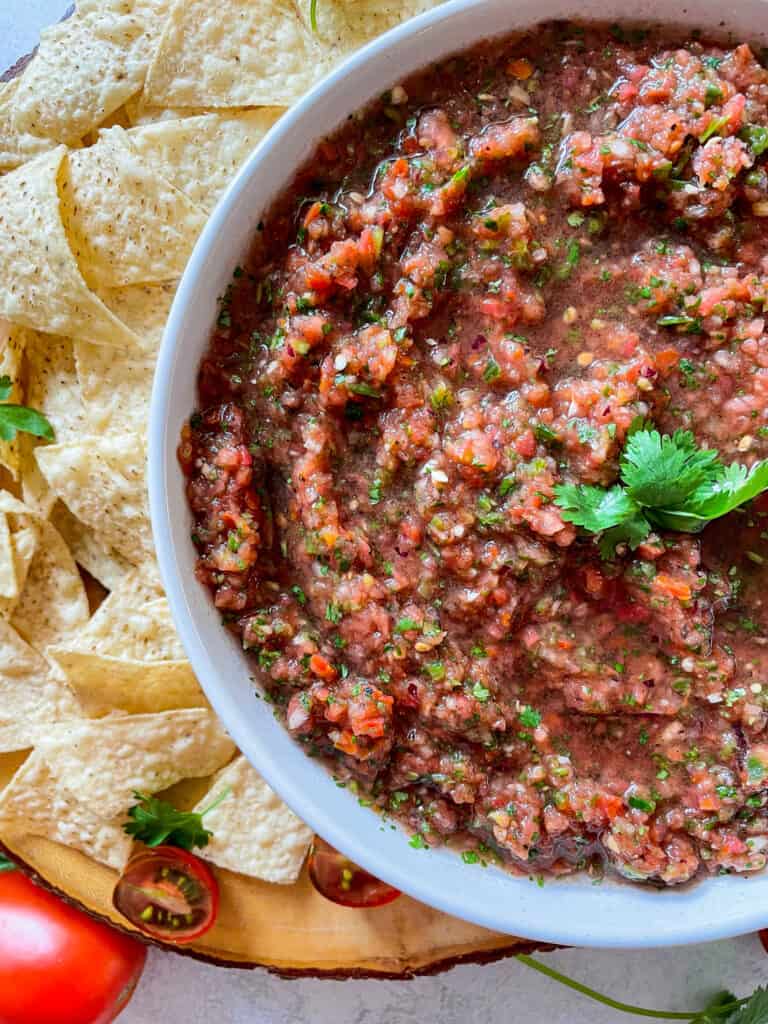 close up of homemade salsa to show texture. salsa in a large white bowl served with tortilla chips