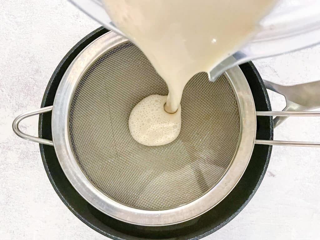 Straining the eggnog to remove any curdled bits