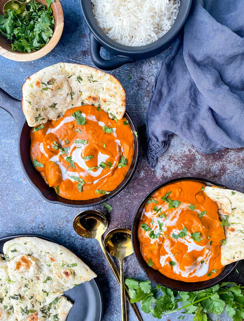two dishes of dairy free butter chicken with naan