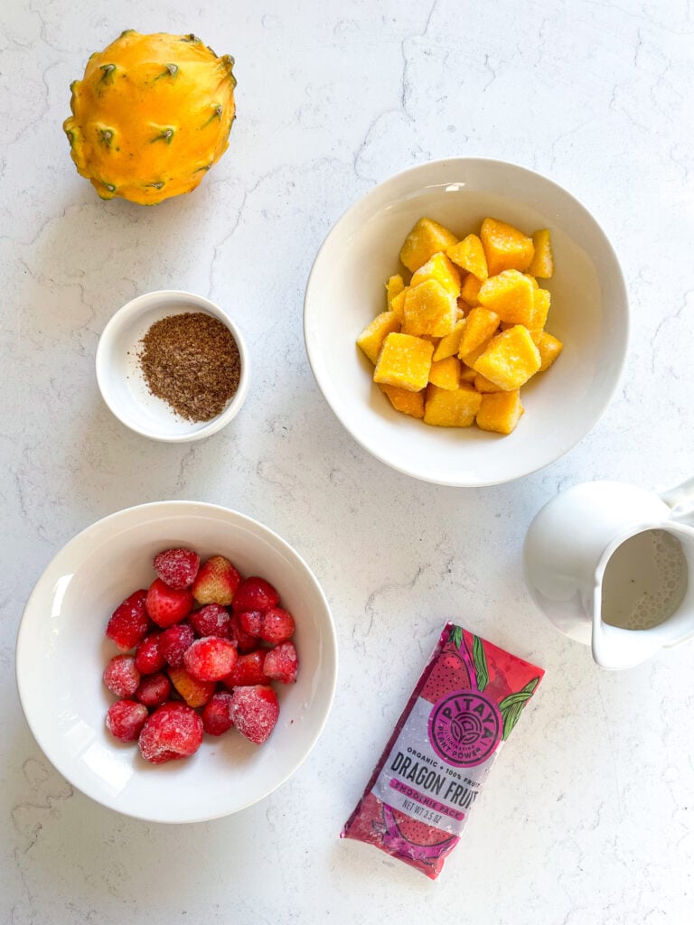 ingredients needed to make a pitaya bowl: frozen mango, frozen dragonfruit packet. frozen strawberries, non-dairy milk. flax seeds, optional
