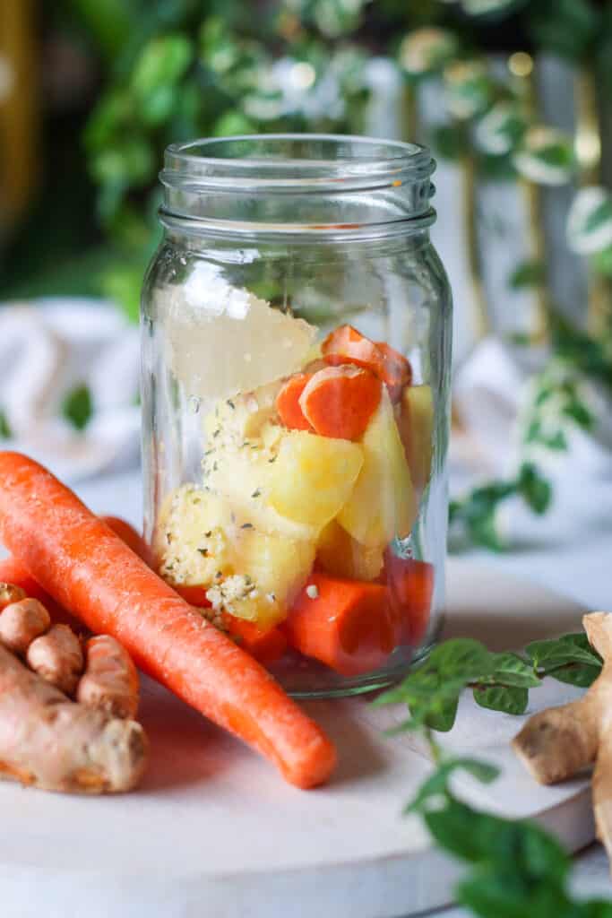 carrot smoothie with carrot ginger turmeric sea moss hemps seeds and pineapple. ingredients shown in a mason jar before blending 