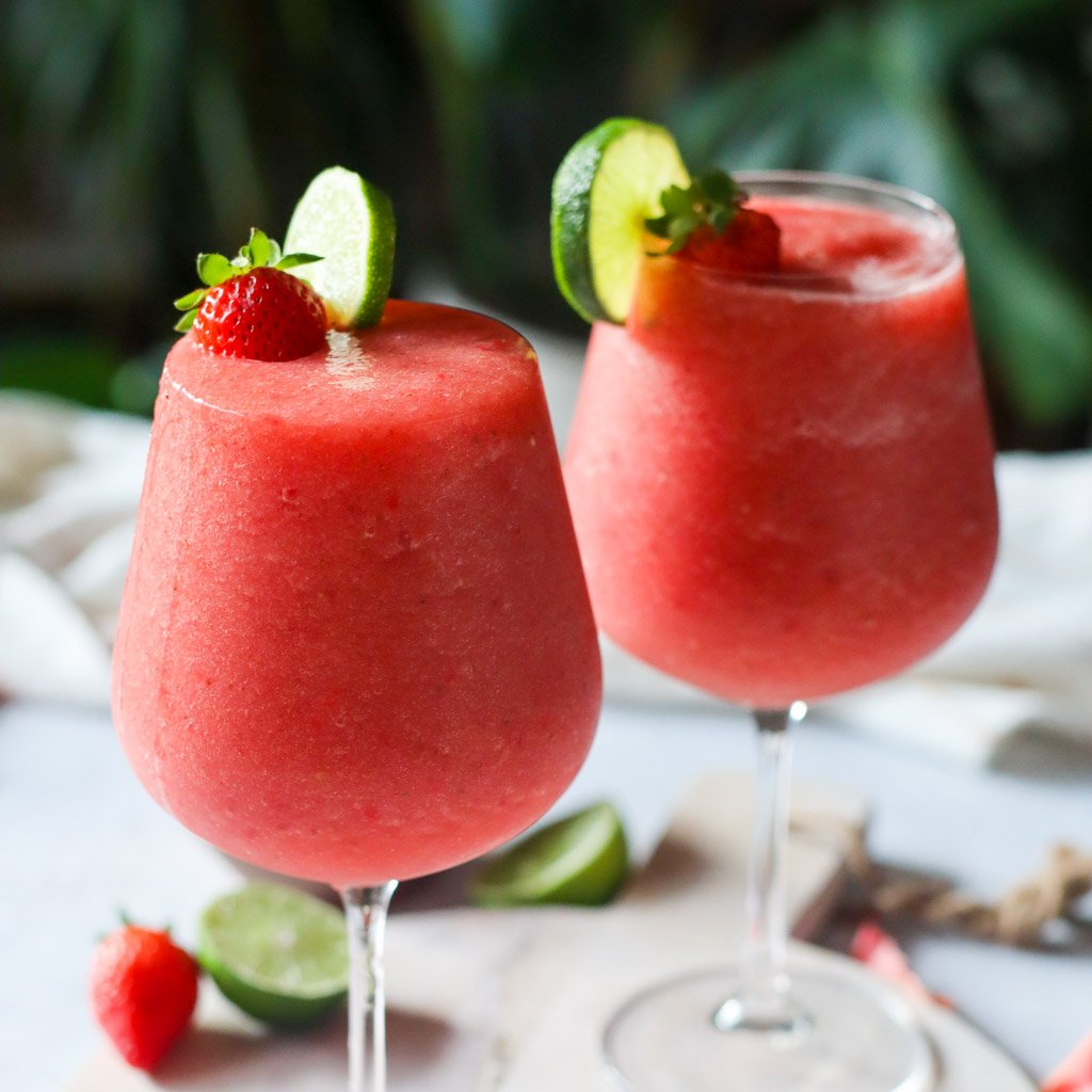 two glasses of strawberry watermelon frose topped with strawberry and lime