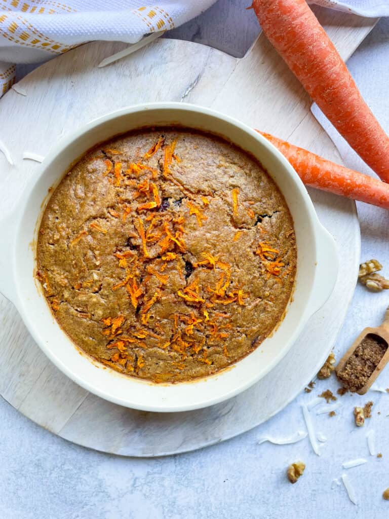 Carrot cake oats in a bowl with two large carrots beside it