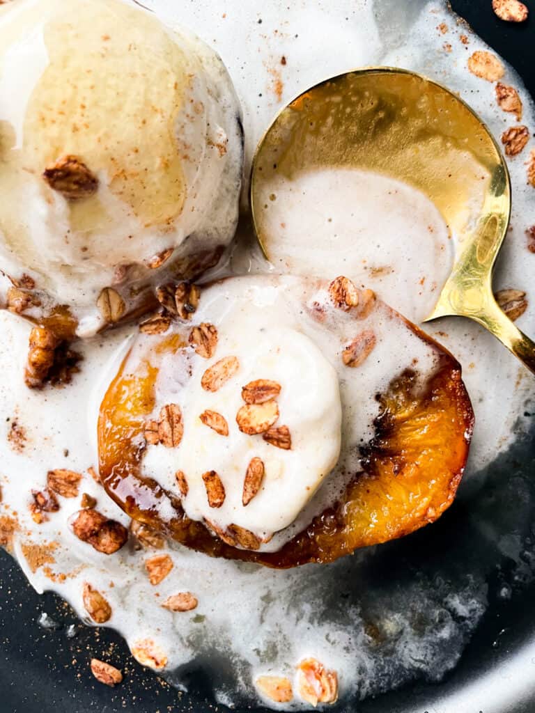 overhead view of peaches covers in slightly melted ice cream with a large gold spoon beside it