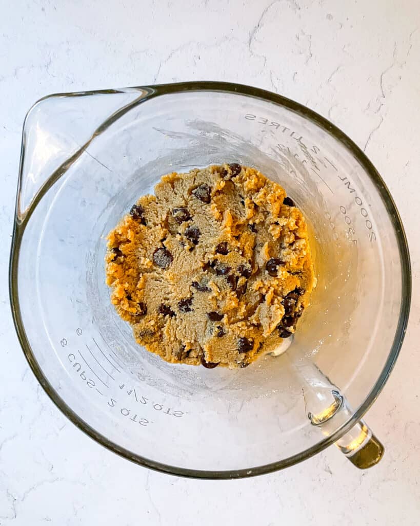 Overhead view of measuring cup containing egg-free chocolate chip cookie dough