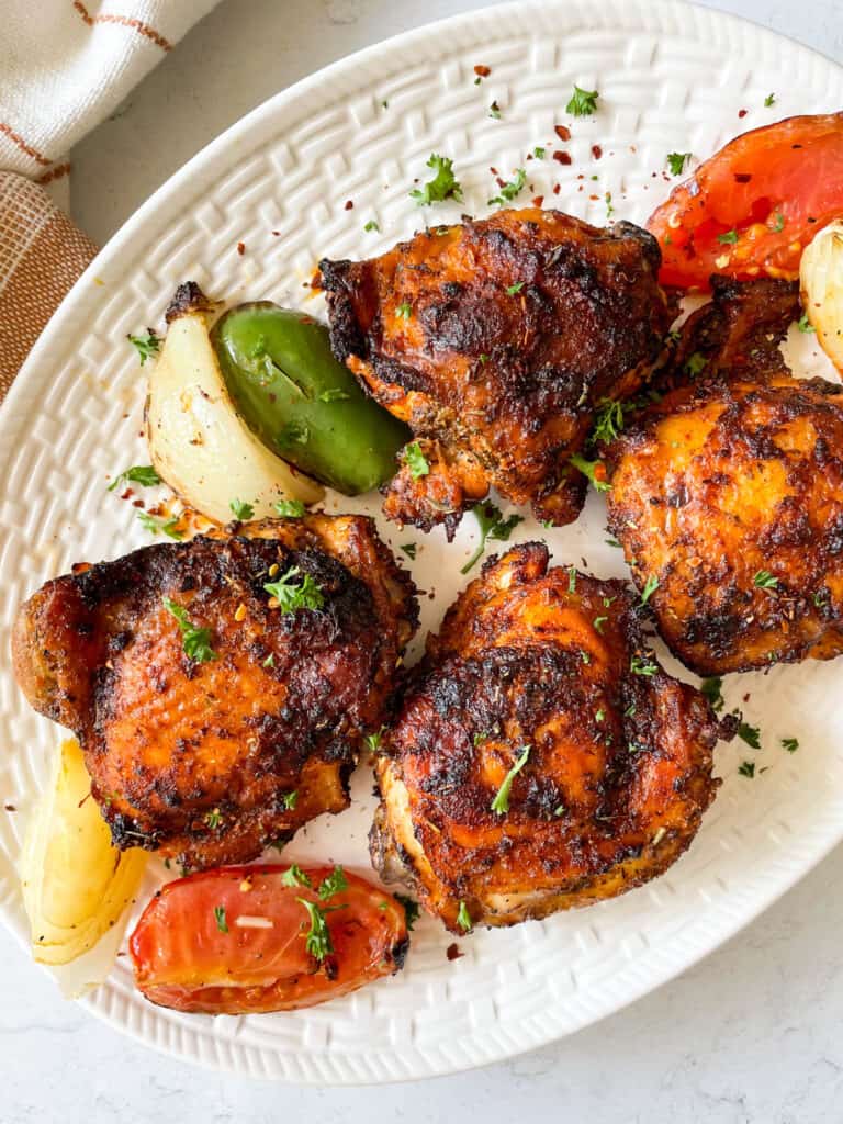 Four crispy chicken thighs with tomatoes and onions
