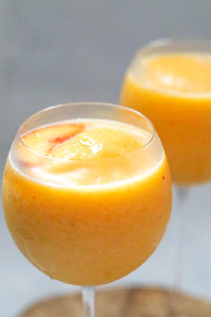two glasses of white wine slushies made with frozen peaches