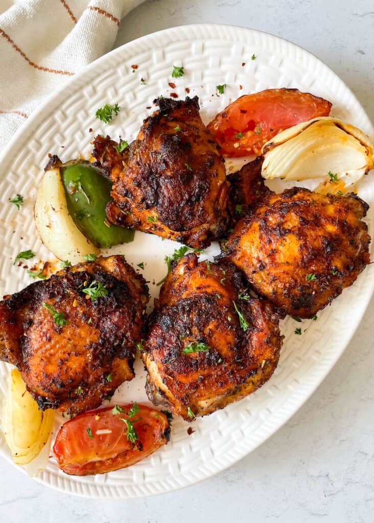 crisp chicken thighs made in the air fryer served on a plate with onions and peppers