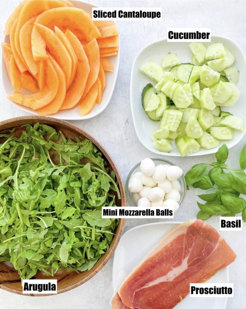 ingredients show to make the salad shown are sliced cantaloupe cucumber prosciutto basil mini mozzarella balls basil and arugula