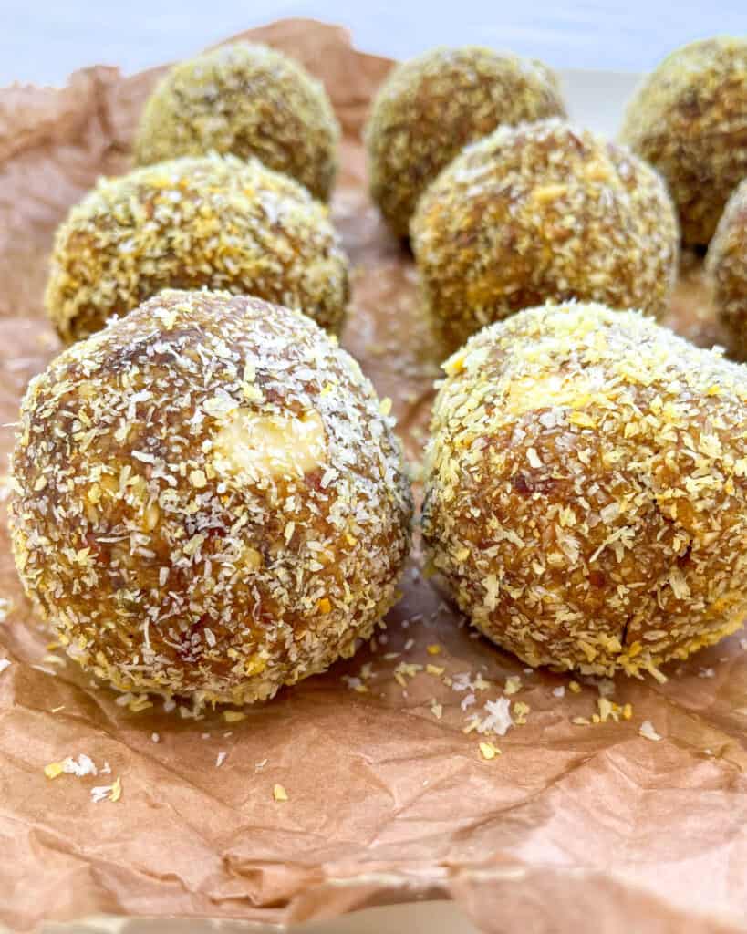 close up of no bake turmeric balls on a parchment lined plate 6 energy balls are shown