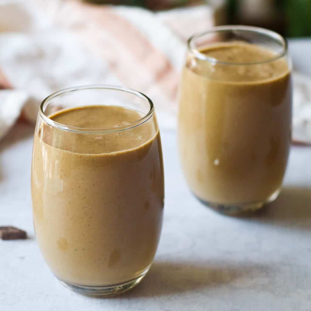 two glasses of a creamy chocolate zucchini smoothie