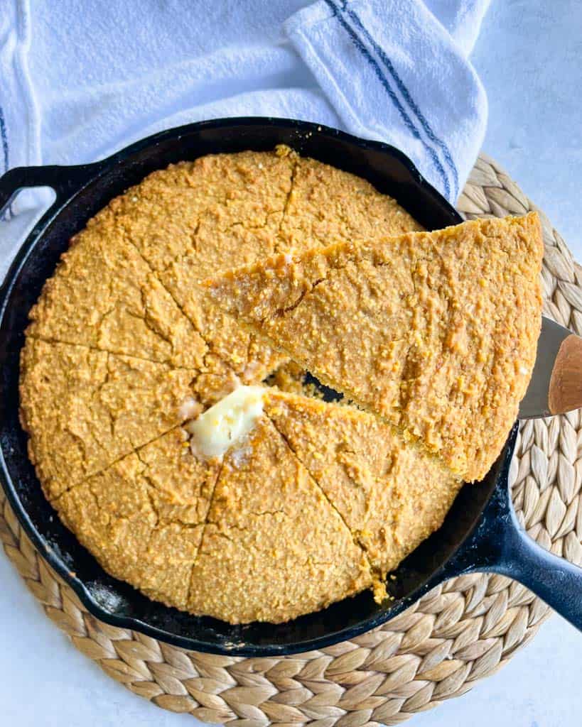 overhead view of a skillet full of sliced cornbread with melted butter at the center