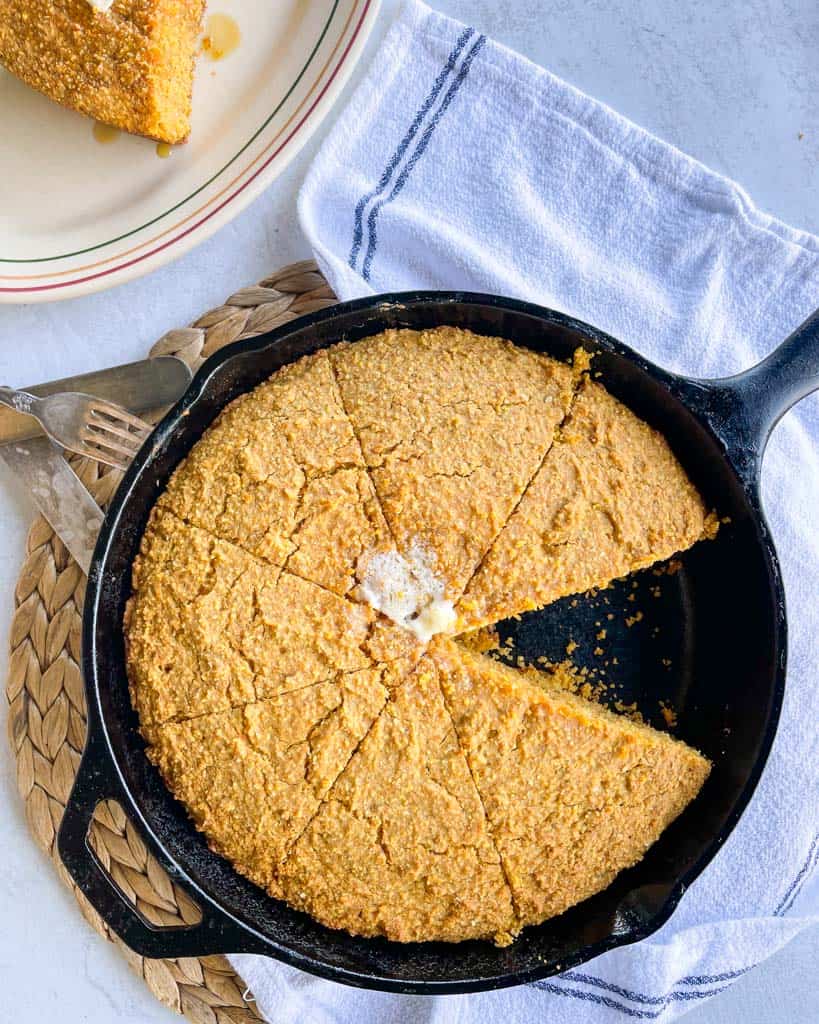 a skillet of cornbread with one slice cut out