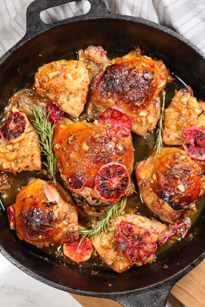 blood orange chicken thighs in a cast iron skillet with rosemary