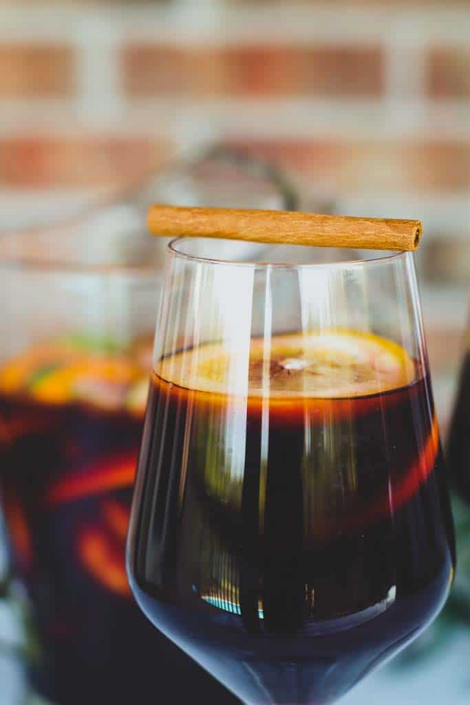 close up view of a glass of sangria garnished with a cinnamon stick