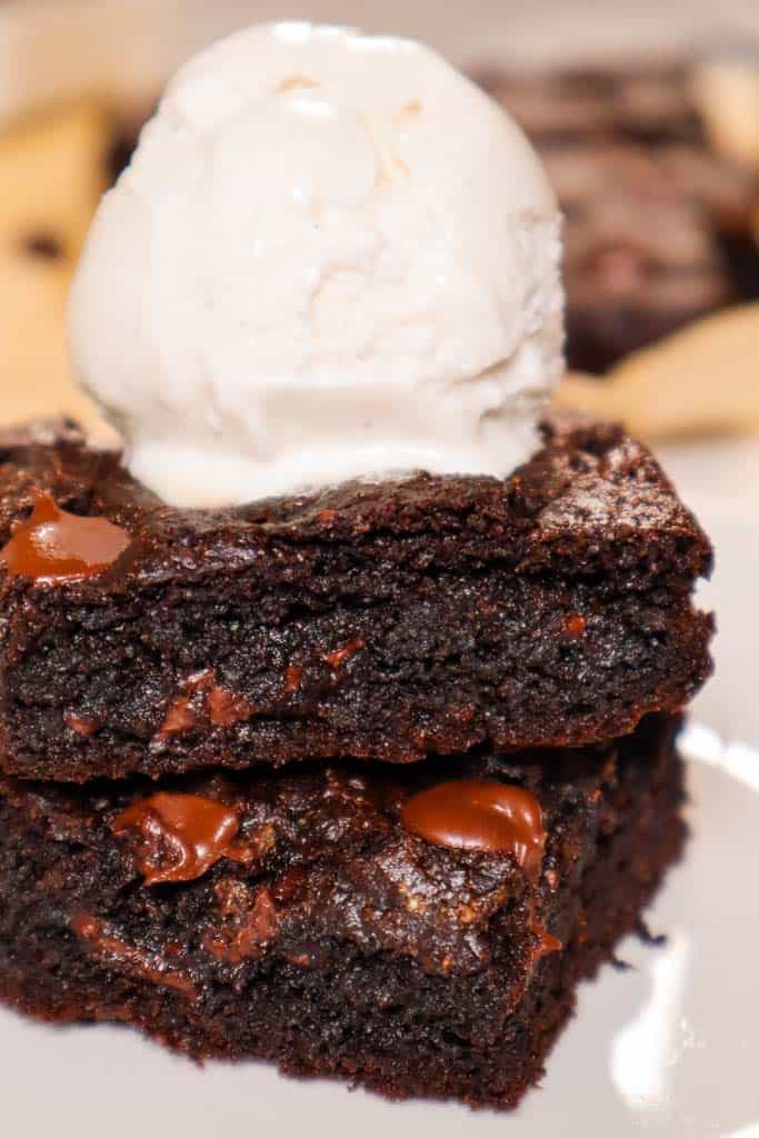 two gluten free vegan brownies stacked with a scoop of vanilla ice cream on top 