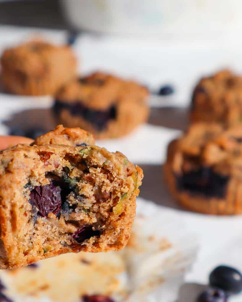 zucchini blueberry muffins with a bit taken to show inside texture