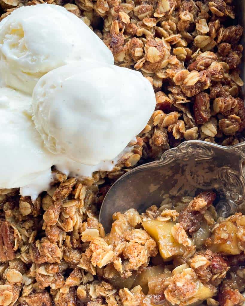 close up view of a spoon inserted in the dessert with a scoop of vanilla ice cream