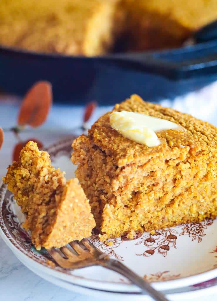 a slice of homemade gluten free pumpkin cornbread cut with a fork and topped with butter