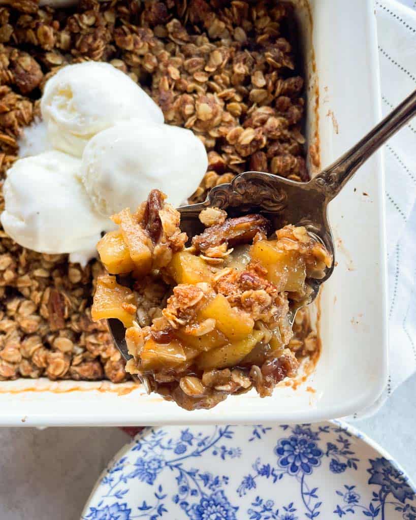 a spoonful of apple crisp over a baking dish full of the dessert