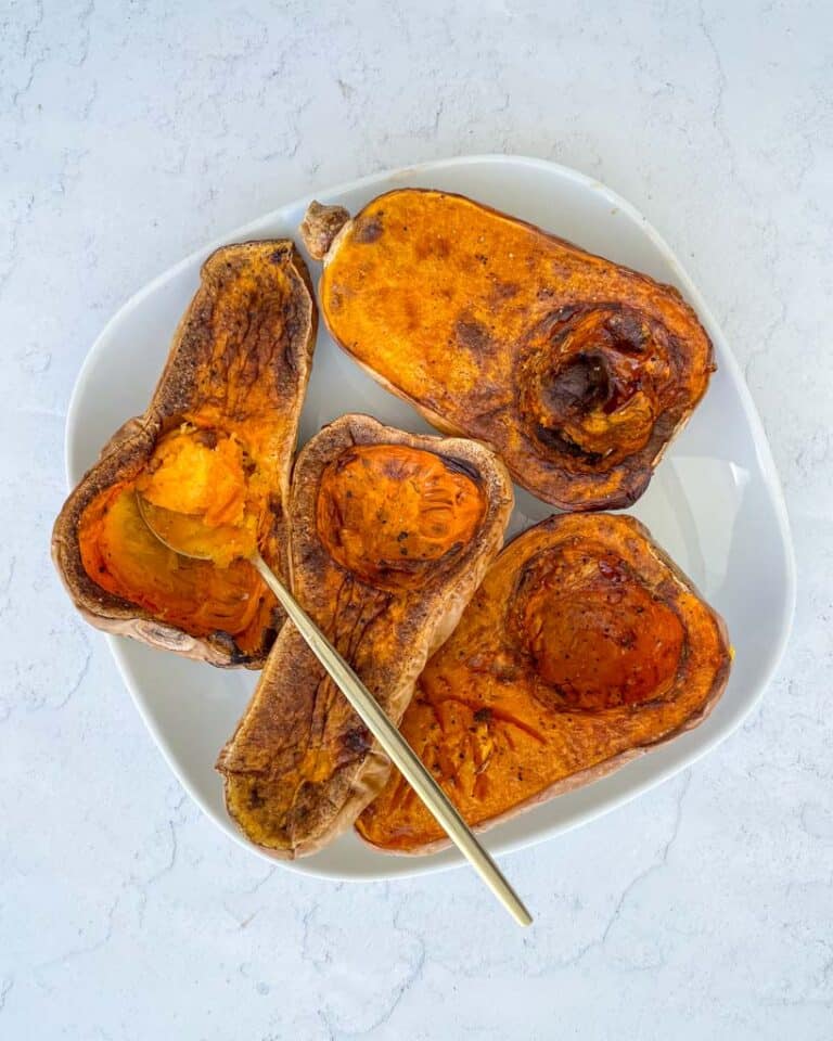four air fried butternut squash halves on a plate with a gold spoon in one of the halves